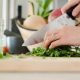 Kniv som skär grönsaker på skärbräda